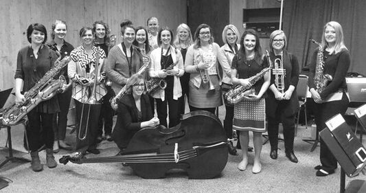 Members of the IWJO posing for a photo with their instruments and smiling.